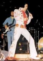 Elvis draagt een witte zijden overall met rood borduurwerk en een rode sjaal. Verder draagt hij struisvogelleren cowboylaarzen en een brede riem met echte edelstenen.